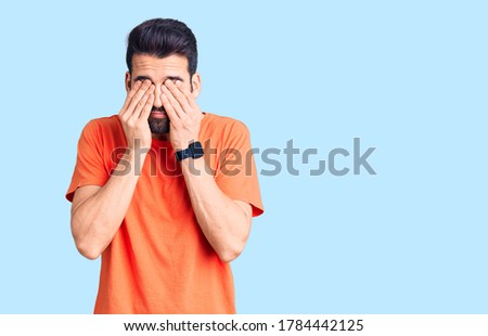 Young handsome man with beard wearing casual t-shirt rubbing eyes for fatigue and headache, sleepy and tired expression. vision problem 
