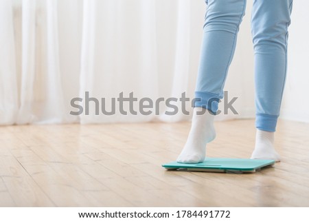 female feet and bathroom scales on wooden floor