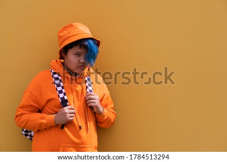 Back to school. Teenage girl with blue hair in an orange hoodie, a Panama hat with a backpack. High school kid.Education.