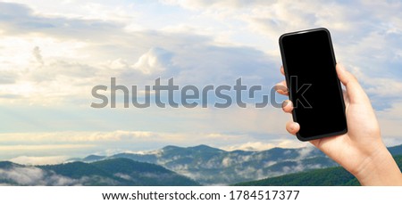 beautiful female hand holding smart phone with black screen against nature moutain with clound background, technology and nature concept. banner and copy space
