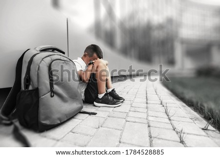 child with backpack in depression is sitting on the floor doesn't want back to school Royalty-Free Stock Photo #1784528885