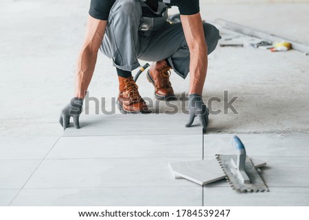Man in grey uniform works indoors in modern big office at daytime.