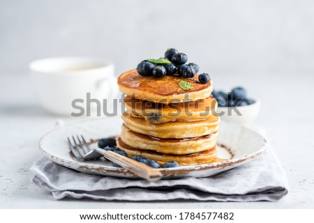Tasty pancakes with blueberries and honey on a plate. Grey background Royalty-Free Stock Photo #1784577482