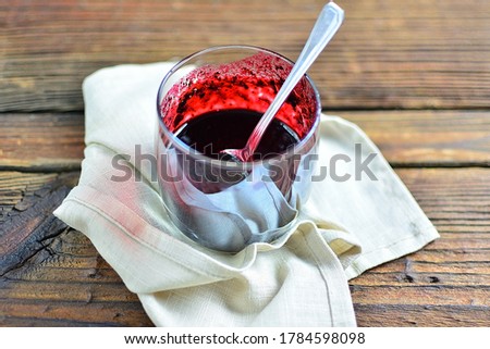 Jam blueberries with sugar in a glass, on a napkin and an old wooden table, copy space