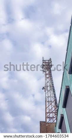 Mobile phone radio antenna tower. Cell tower against a cloudy sky, vertical photo
