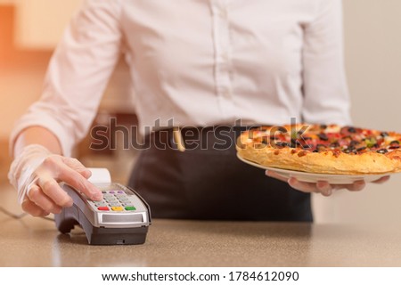 Service payment for services, the waiter pays for the pizza with gloves in connection with the coronavirus, without contact payment