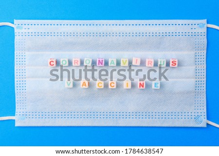 Cubes form the text Coronavirus vaccine on the background of a medical surgical mask.