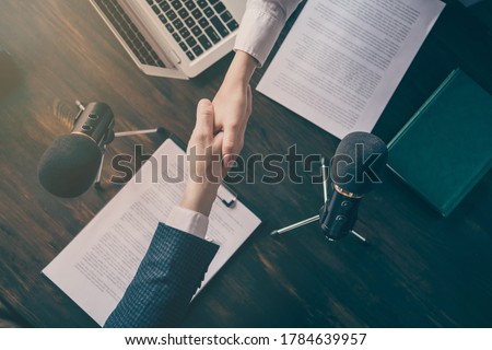 High angle top above view cropped photo of two business people, journalism press conference shake arms successful reportage microphone on table office indoors