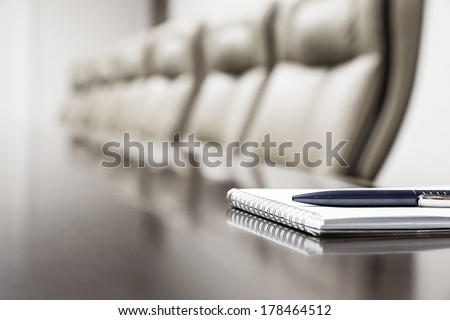 Closeup of notepad for agenda kept on table in empty corporate conference room before business meeting Royalty-Free Stock Photo #178464512
