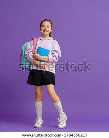 Back to school and happy time! Cute industrious child on color paper wall background. Kid with backpack. Girl ready to study. Royalty-Free Stock Photo #1784650217