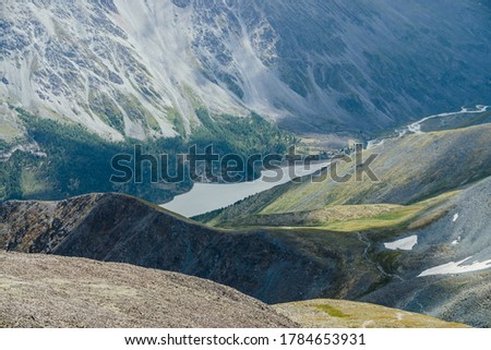 Awesome aerial view to beautiful valley with mountains lake and giant textured slopes with forest. Atmospheric alpine landscape with big rocky hills and huge mountains. Nature patterns on mountainside