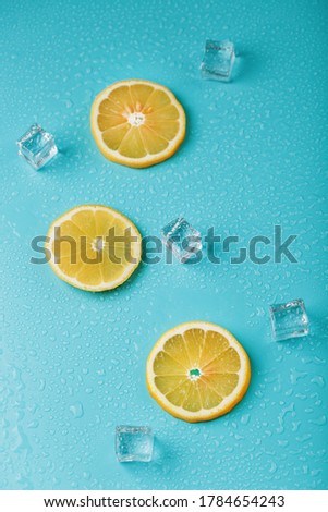 Fresh lemon with ice and drops on a blue background.