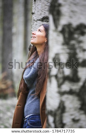 Pale toned picture of a youg woman walking in autumn park