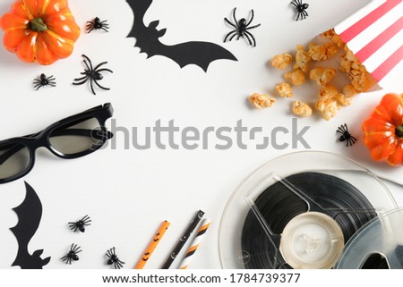 Halloween scary movie concept. Flat lay composition with popcorn, orange pumpkins, bobbins, glasses, halloween decorations on white table. Top view.