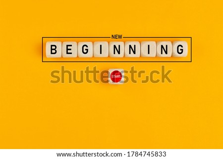 Starting a new beginning concept. The word new beginning on wooden cubes with a start button on yellow background.  Royalty-Free Stock Photo #1784745833