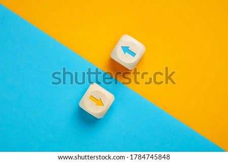 Arrow icons in contrast on wooden cubes moving towards opposite directions. Competition, diversity, opposition or confrontation concept.  Royalty-Free Stock Photo #1784745848