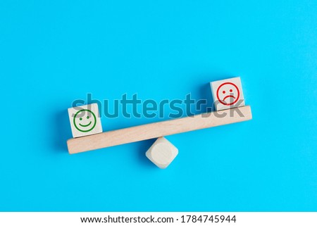 Happy and sad smiley faces on wooden seesaw. Customer satisfaction, evaluation or positive feedback concept.  Royalty-Free Stock Photo #1784745944