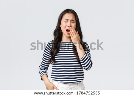 Lifestyle, people emotions and casual concept. Sleepy tired woman working late in office, close eyes and yawning, want go bad. Asian girl woke up early, need coffee, stand white background