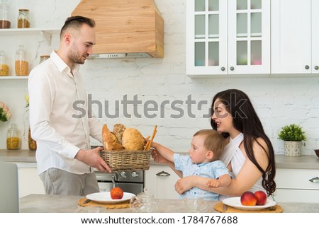 happy family in home kitchen married couple with a small child - baby takes bread