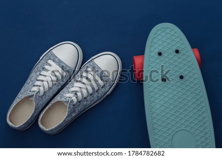 Cruiser board with sneakers on a classic blue background. Youth entertainment. Top view. Flat lay