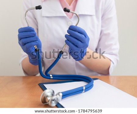 female doctor in gloves taking Stethoscope at doctor working table close up. Healthcare and medical concept.