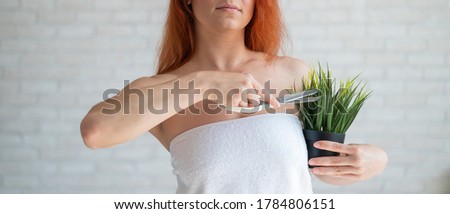 Close-up. Cropped. A woman shears a plant in a pot with a scissors simulating the removal of unwanted hair vegetation on the body. Depilation in the armpit area. Smooth skin after hair removal.