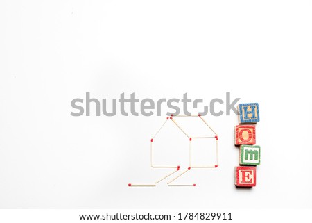 House made of matchsticks on an isolated white background with the word 'home' written in blocks alongside