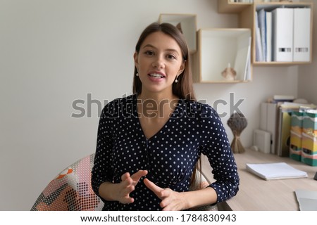 Portrait of young Caucasian female coach or blogger talk on video cam, have online webcam conversation, millennial woman speaker influencer speak on virtual event call or conversation at home Royalty-Free Stock Photo #1784830943