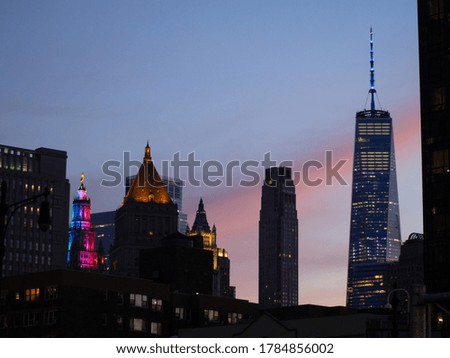 New York City skyline with colorful lights during a pink sunset.