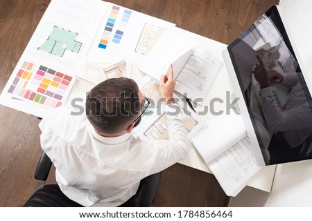 A man makes an estimate of construction work. Calculating the cost of a new home. Construction engineer at his Desk. Work on a construction project. Royalty-Free Stock Photo #1784856464
