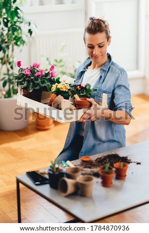 Happy woman holding a wooden box full of spring flowers