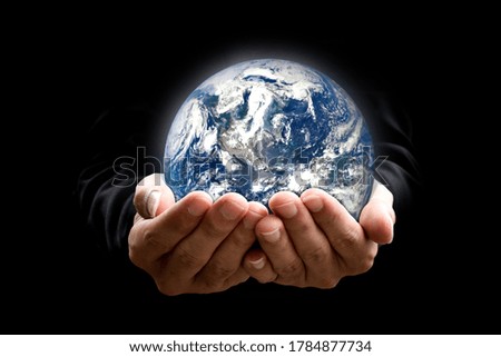 Environment concept. Earth in hands on black background. Elements of this image furnished by NASA