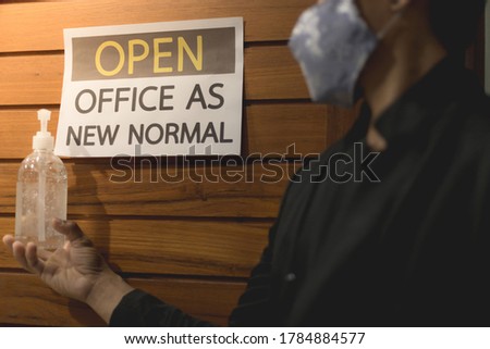 Business owner wears masks and hand is holding alcohol gel to label for open office. The concept is opening office after the COVID-19 situation, follows the new normal life. selecttive focus