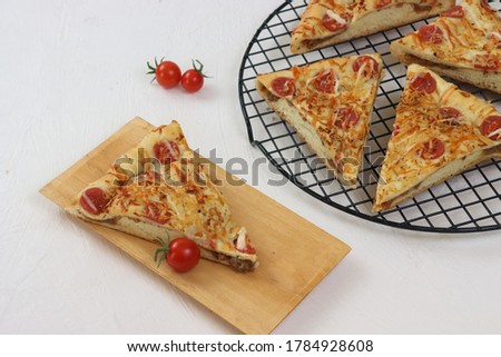 Roti pizza. Pizza bread garnished with fresh oregano and cherry tomato on wooden pizza board.
