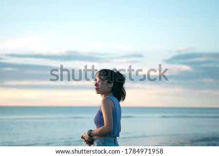 Portrait of young adult asian woman seaside beach in the morning with sunrise.