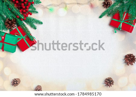 Christmas composition. Bright christmas gift, pine cones, fir branches, light, garland on white corrugated paper background. Top view, copy space