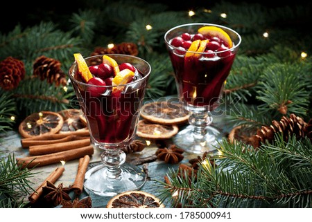 Christmas mulled red wine with addition cinnamon sticks, anise stars, cranberry and   oranges  in  glass on rustic wooden table