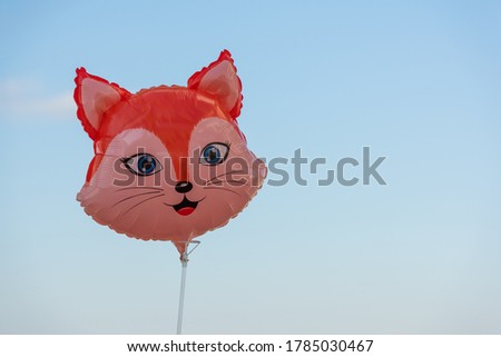 A cute toy fox smiley balloon on sky background
