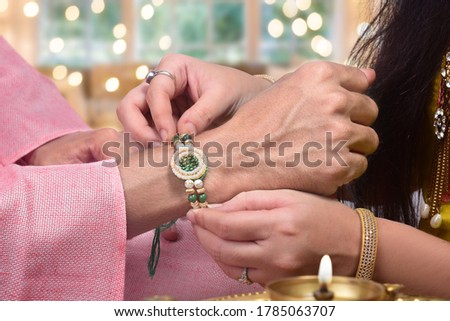 Closeup shot of sister tying rakhi on her brother's wrist, raksha bandhan Royalty-Free Stock Photo #1785063707