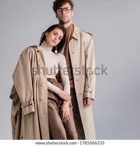 stylish young couple looking at camera while posing in autumn clothes isolated on grey Royalty-Free Stock Photo #1785066233