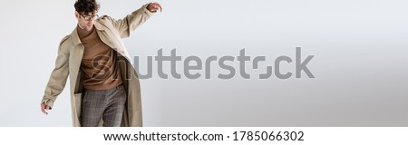 website header of fashionable man balancing while posing on grey Royalty-Free Stock Photo #1785066302