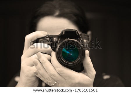 Woman photographer photographing with a camera isolated on black background.