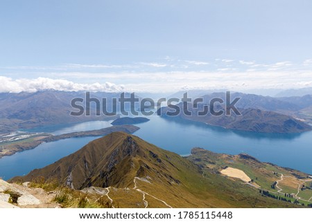The view from the summit of Roys Peak over Lake Wanaka and the mountains of the Southern Alps as clouds roll over them.