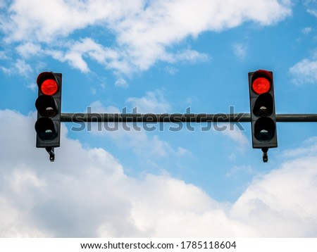 Two traffic lights showing red color against blue sky.