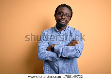 Young handsome african american man wearing shirt and glasses over yellow background skeptic and nervous, disapproving expression on face with crossed arms. Negative person. Royalty-Free Stock Photo #1785149732
