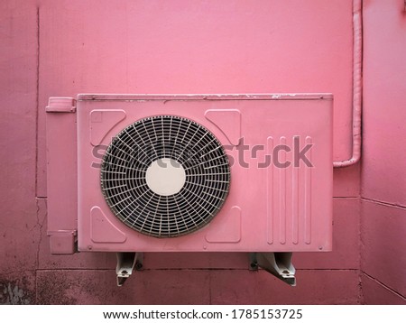 Pink color air conditioner condenser unit outside pink building.