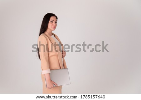 Successful business woman on grey background with copy space. Director in beige strict suit with laptop