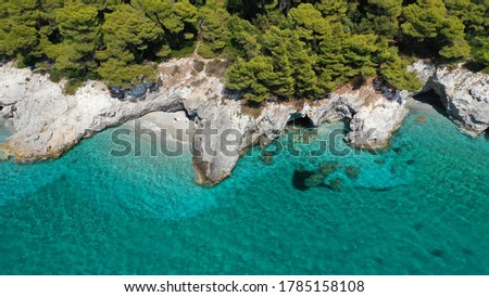 Aerial drone photo of secluded rocky cove near turquoise pebble paradise beach of Kastani covered with pine trees, Skopelos island, Sporades, Greece