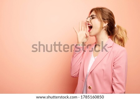 young pretty blonde woman profile view, looking happy and excited, shouting and calling to copy space on the side. business concept