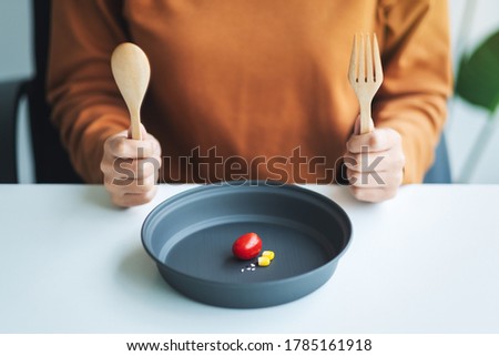 Closeup image of a woman holding spoon and fork to eat small amount of food for diet concept Royalty-Free Stock Photo #1785161918